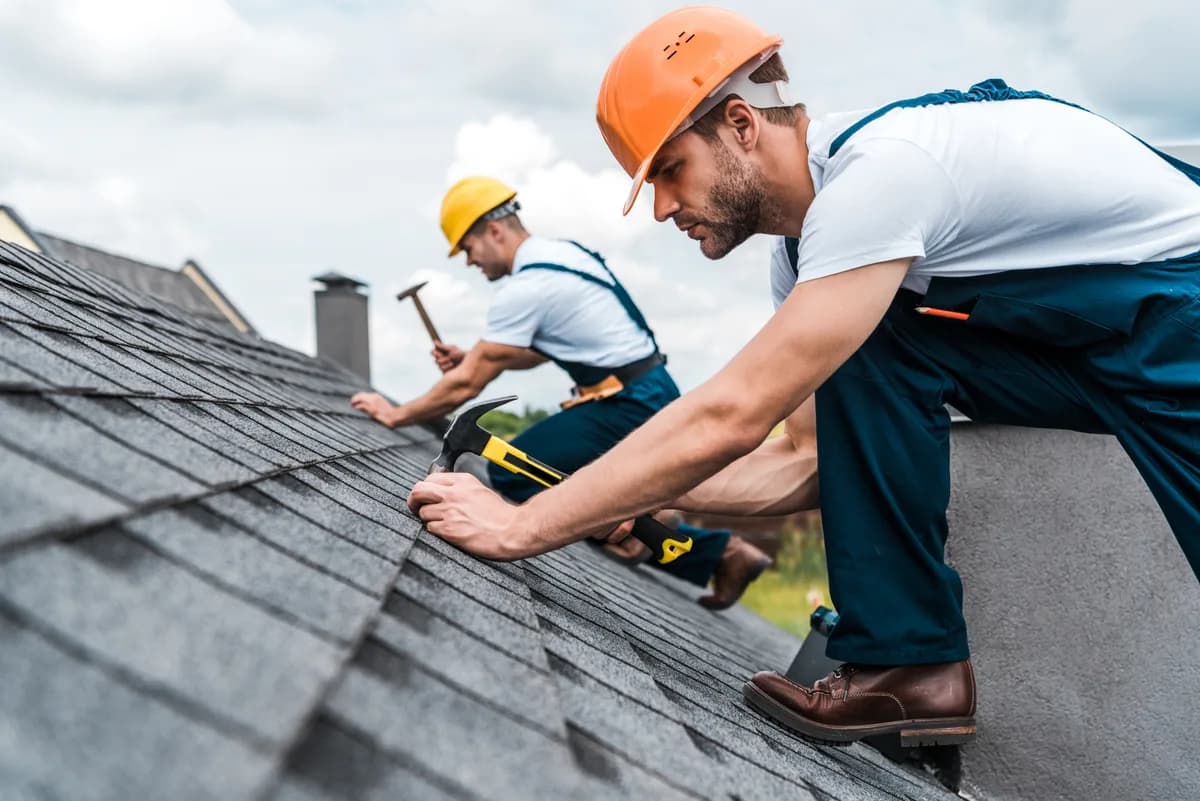 Roofers installing asphalt shingles on a pitched roof